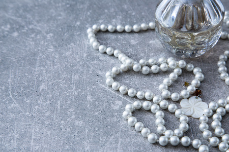 a strand of pearls and perfume on a stone backgroundの写真素材