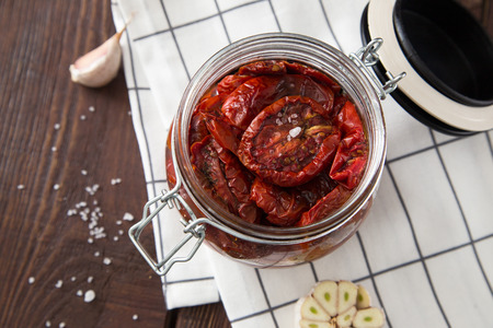 Sun dried tomatoes with herbs and sea salt in olive oil in a glass jar.の写真素材