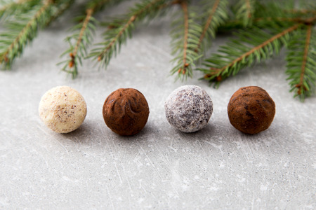 Assorted chocolate truffles with cocoa powder, coconut and chopped hazelnuts on a dessert plate.の写真素材
