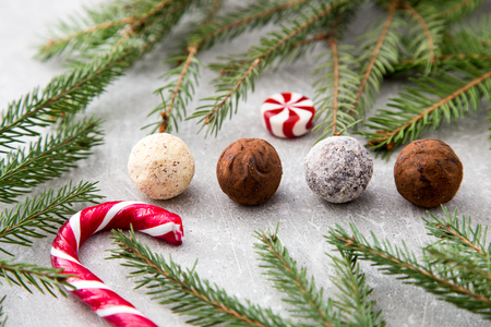Assorted chocolate truffles with cocoa powder, coconut and chopped hazelnuts on a dessert plate.の写真素材