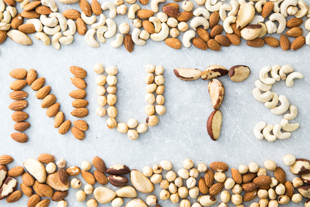 Word NUTS spelled with various nuts on stona background. Assorted mixed nuts.の写真素材