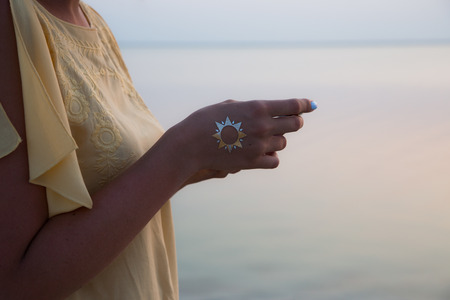 hand of a woman meditating in a yoga pose on the beach at sunset.