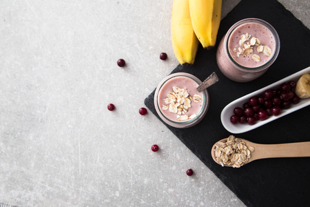 Smoothie of banana and cranberries with yogurt and oats on an slate Board.の写真素材