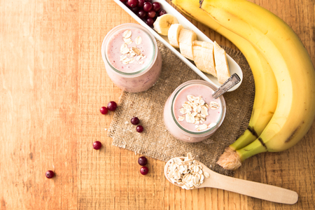 Smoothie of banana and cranberries with yogurt and oats on an old table.の写真素材