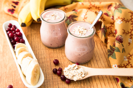 Smoothie of banana and cranberries with yogurt and oats on an old table.の写真素材