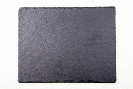 Textured slate board for dishes on light background.