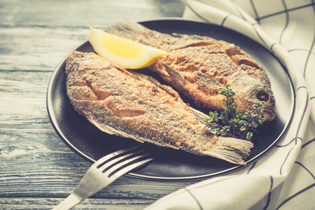 Marinated fried fish carp. Spicy fish fry with spices and lemon on plate, selective focusの写真素材