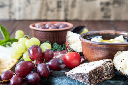 Cheese and meat appetizer selection. Variety of cheese, salami, prosciutto, bread, baguette, grapes, olives.の写真素材