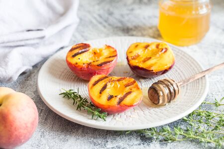 Summer dessert: Cooking Ripe grilled peaches with honey/の写真素材