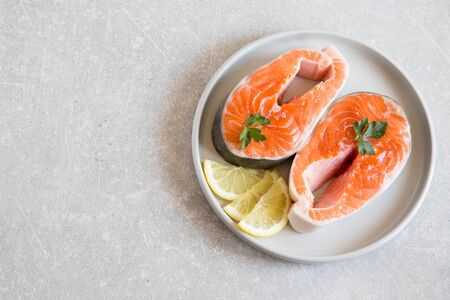 fresh fish. fresh salmon steaks with lemon in a light plate.の写真素材