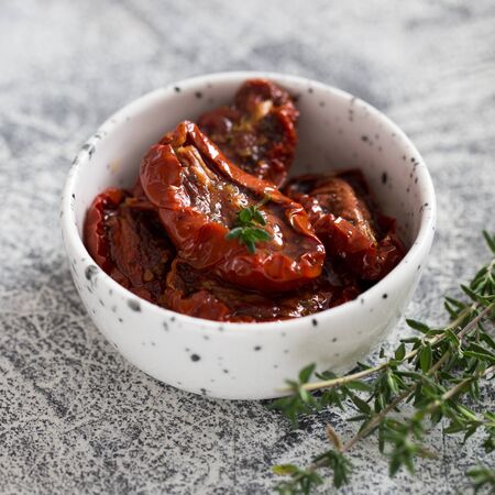 sun-dried tomatoes in a plate on a light concrete background.の写真素材