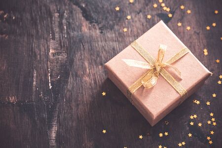 gift box with golden bow on wooden table with copy space, christmas background.の写真素材
