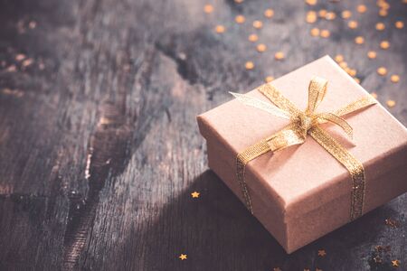 gift box with golden bow on wooden table with copy space, christmas background.の写真素材