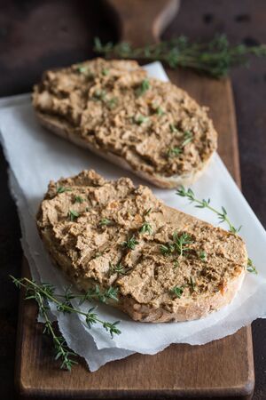 Fresh homemade chicken liver pate. Chicken liver pate on bread and in jar on a dark background/の写真素材