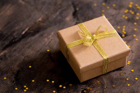 gift box with golden bow on wooden table with copy space, christmas background.の写真素材
