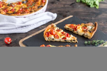 Vegetarian homemade pie, Quiche with cherry tomatoes, eggplant and feta cheese on a dark background.の写真素材
