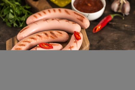 grilled sausages with ketchup, herbs and hot chili peppers.の写真素材