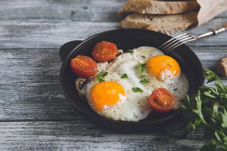 Fried egg. Close up view of the fried egg on a frying pan with cherry tomatoes and parsley.の写真素材