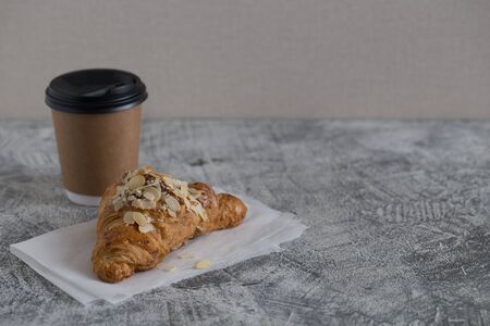 fresh croissant and coffee in a paper cup on a light background.の写真素材