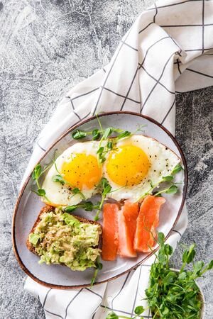 Egg breakfast. Healthy nutritious breakfast with eggs, salmon, avocado sandwich and sprouted pea seeds.の写真素材