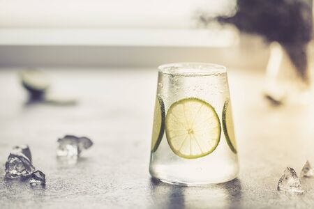 a glass of fresh drinking water and a lime. or Alcoholic Gin and Tonic with a Lime/の写真素材