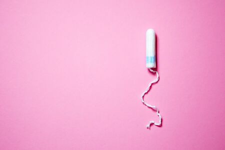 Medical female tampon on a pink background with copy space. Hygienic white tampon for women. Cotton...