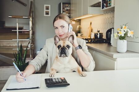 Beautiful young woman working from home with her dog. Many stuff to do today. woman work as a freelancerの写真素材