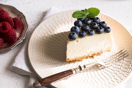 Slice Of Classical New York Cheesecake with blueberries On White Plate. Closeup View. Home bakery concept/の写真素材