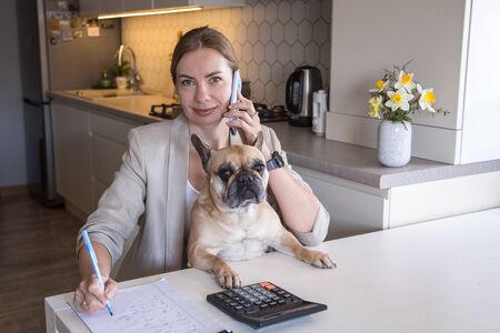 Beautiful young woman working from home with her dog. Many stuff to do today. woman work as a freelancerの写真素材