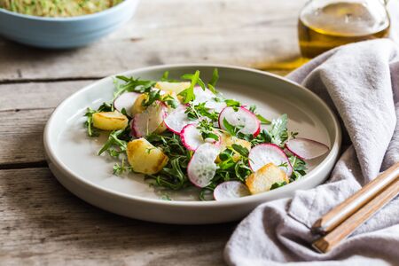 fresh salad with arugula, radish, baked potatoes and aromatic herbs with olive oil.の写真素材