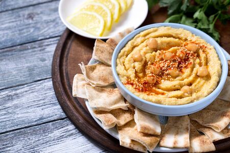 A bowl of creamy homemade hummus with olive oil and pita chips. traditional vegan healthy meal.の写真素材