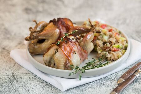 delicious baked quail with bacon and side dish.の写真素材