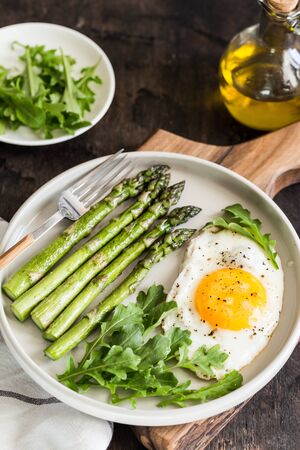 Healthy homemade breakfast with asparagus, fried egg and arugula. quarantine healthy eating concept. keto dietの写真素材