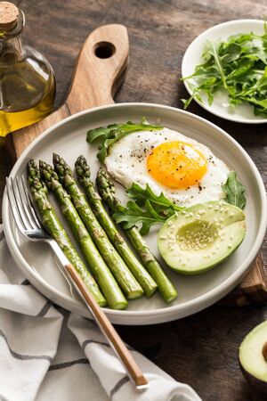 Healthy homemade breakfast with asparagus, fried egg, avocado and arugula. quarantine healthy eating concept. keto dietの写真素材