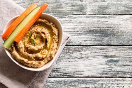 hummus sauce in a bowl, sesame seeds, olive oil, cucumber and carrots on a light backgroundの写真素材