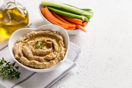 hummus sauce in a bowl, sesame seeds, olive oil, cucumber and carrots on a light backgroundの写真素材