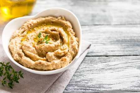 hummus sauce in a bowl, sesame seeds, olive oil, cucumber and carrots on a light backgroundの写真素材