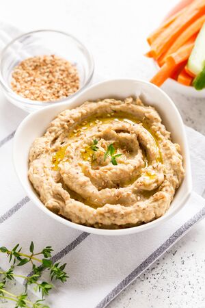 hummus sauce in a bowl, sesame seeds, olive oil, cucumber and carrots on a light backgroundの写真素材