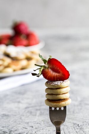 Tiny pancakes for breakfast. mini pancakes on a fork with strawberriesの写真素材