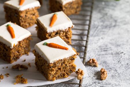 pieces of carrot cake with walnuts with icing cream on a light background. tinting. selective focus/の写真素材