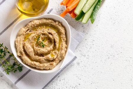 hummus sauce in a bowl, sesame seeds, olive oil, cucumber and carrots on a light backgroundの写真素材