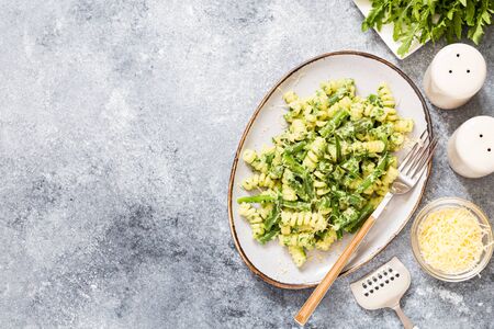 pasta with green vegetables and creamy sauce. fusilli pasta with asparagus beans and spinach on grey stone backgroundの写真素材