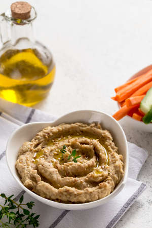 hummus sauce in a bowl, sesame seeds, olive oil, cucumber and carrots on a light backgroundの写真素材