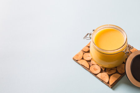 Ghee or clarified butter in jar and wooden spoon on blue background. Top view. Copyspace. Ghee butter have healthy fat and is a common cooking ingredient in many of the Indian foodの写真素材