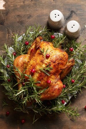 baked whole chicken with rosemary garlic and cranberries on a wooden dark background. roasted chicken.の写真素材