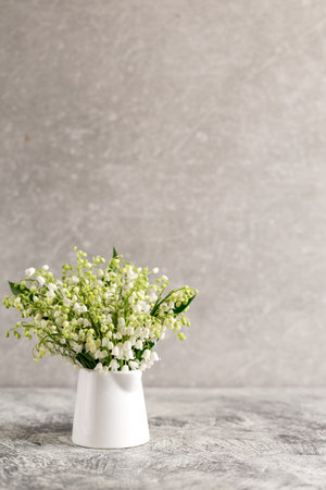 bouquet of lilies of the valley in a white glass on a gray concrete background.の写真素材