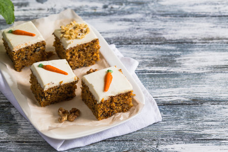 pieces of carrot cake with walnuts with icing cream on a light background. tinting. selective focus /の写真素材