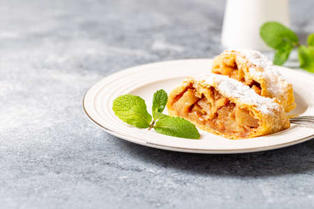 homemade flavored apple strudel in a plate on a gray concrete background with space for text,の写真素材