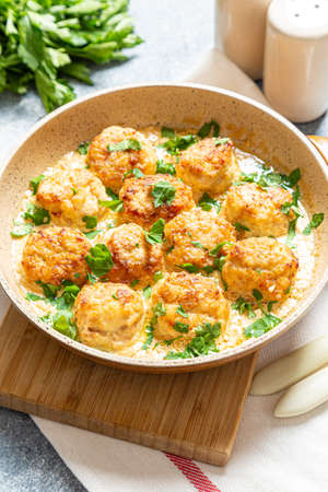 meatballs in white sauce in a frying pan on a gray background, comfortable homemade healthy foodの写真素材