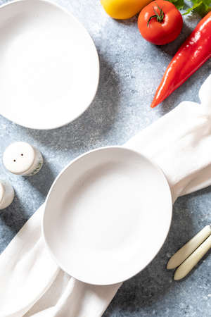 empty plates and napkin on gray background. food preparation and self-care concept.の写真素材